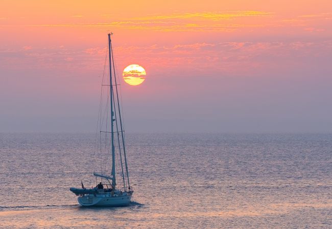 Barco a velejar ao pôr-do-sol